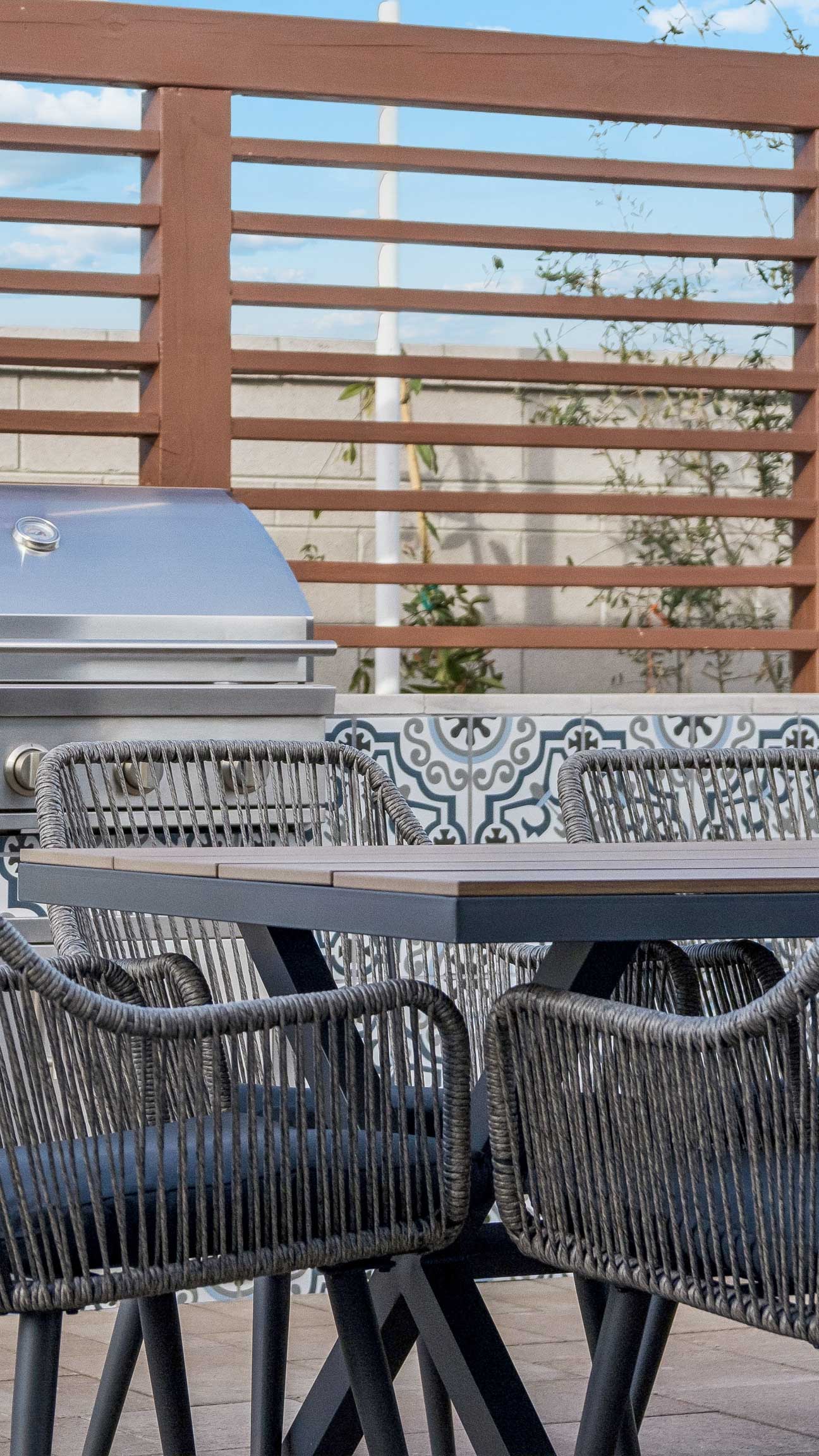 Editorial lifestyle photo detail shot of ceramic outdoor kitchen italian tile station with grill, table and chairs perfect for entertaining- new construction homes near Amarillo ranch palomino ranch in Maricopa AZ with USDA new construction