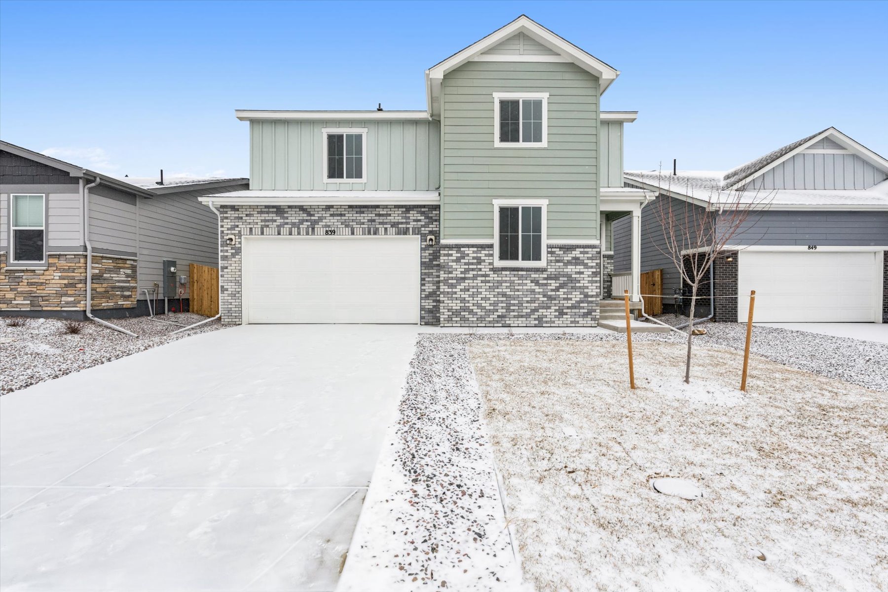 A house with a garage and a snow covered yard.