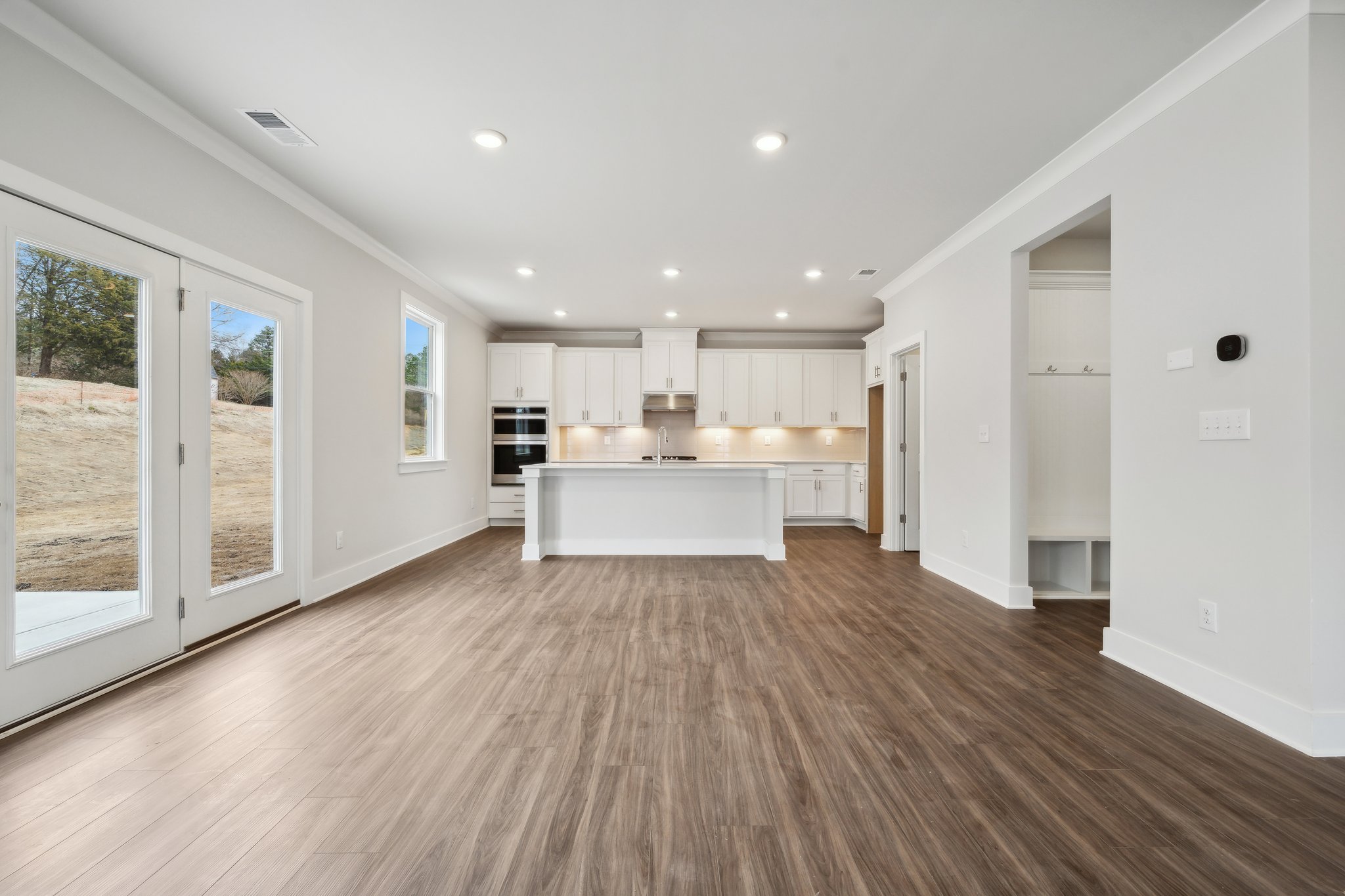 A large white kitchen with a wood floor.