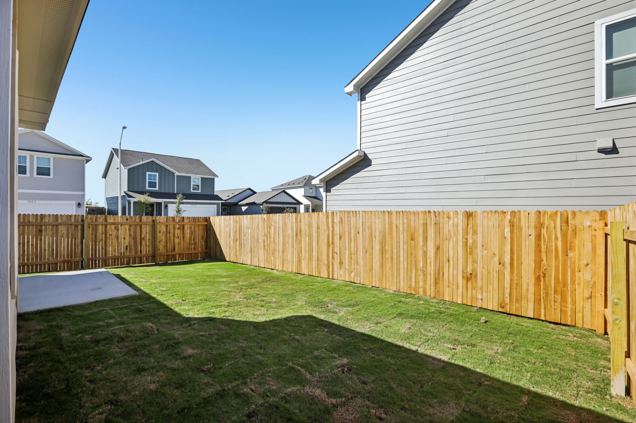 A fenced yard with houses in the background.
