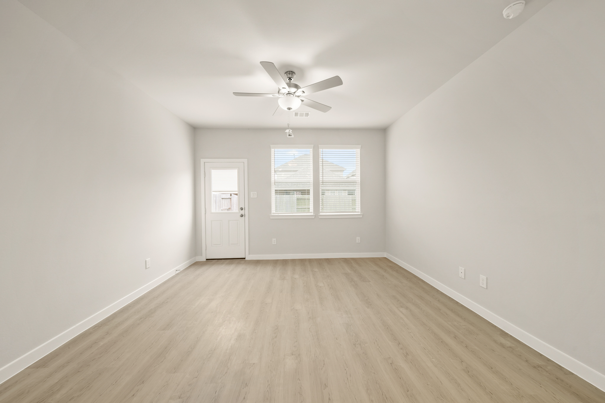 A room with a ceiling fan and a wood floor.