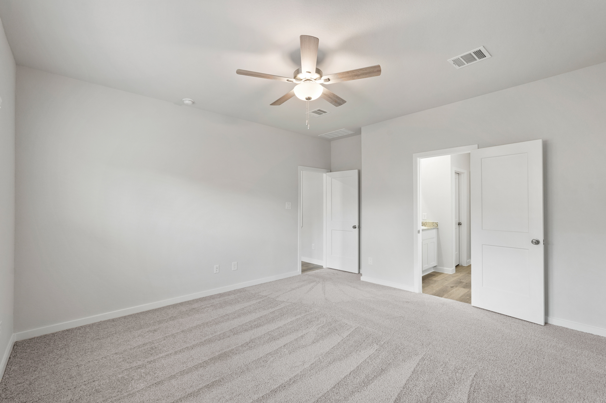A room with a ceiling fan and white cabinets.