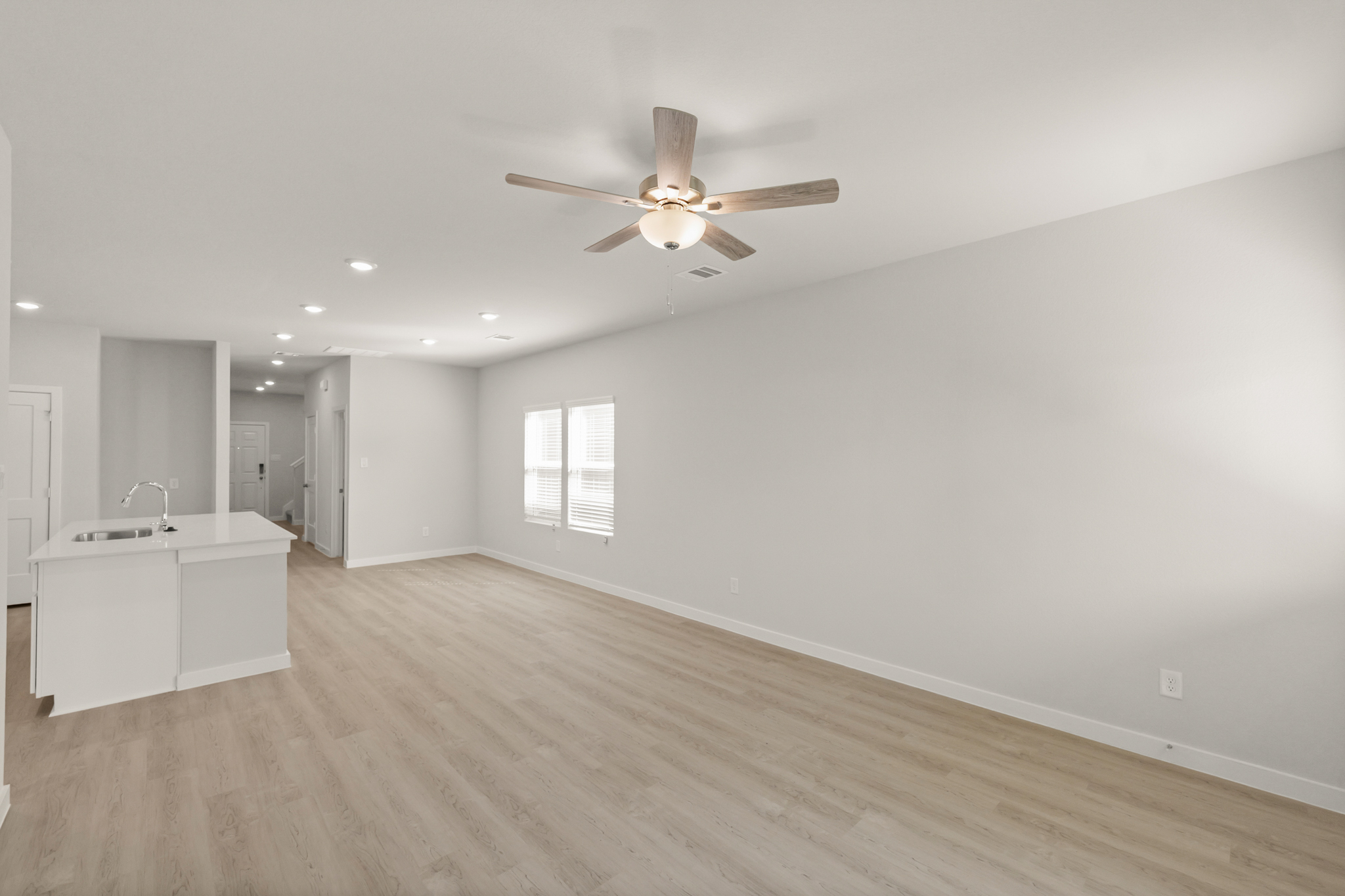 A room with a ceiling fan and a wood floor.