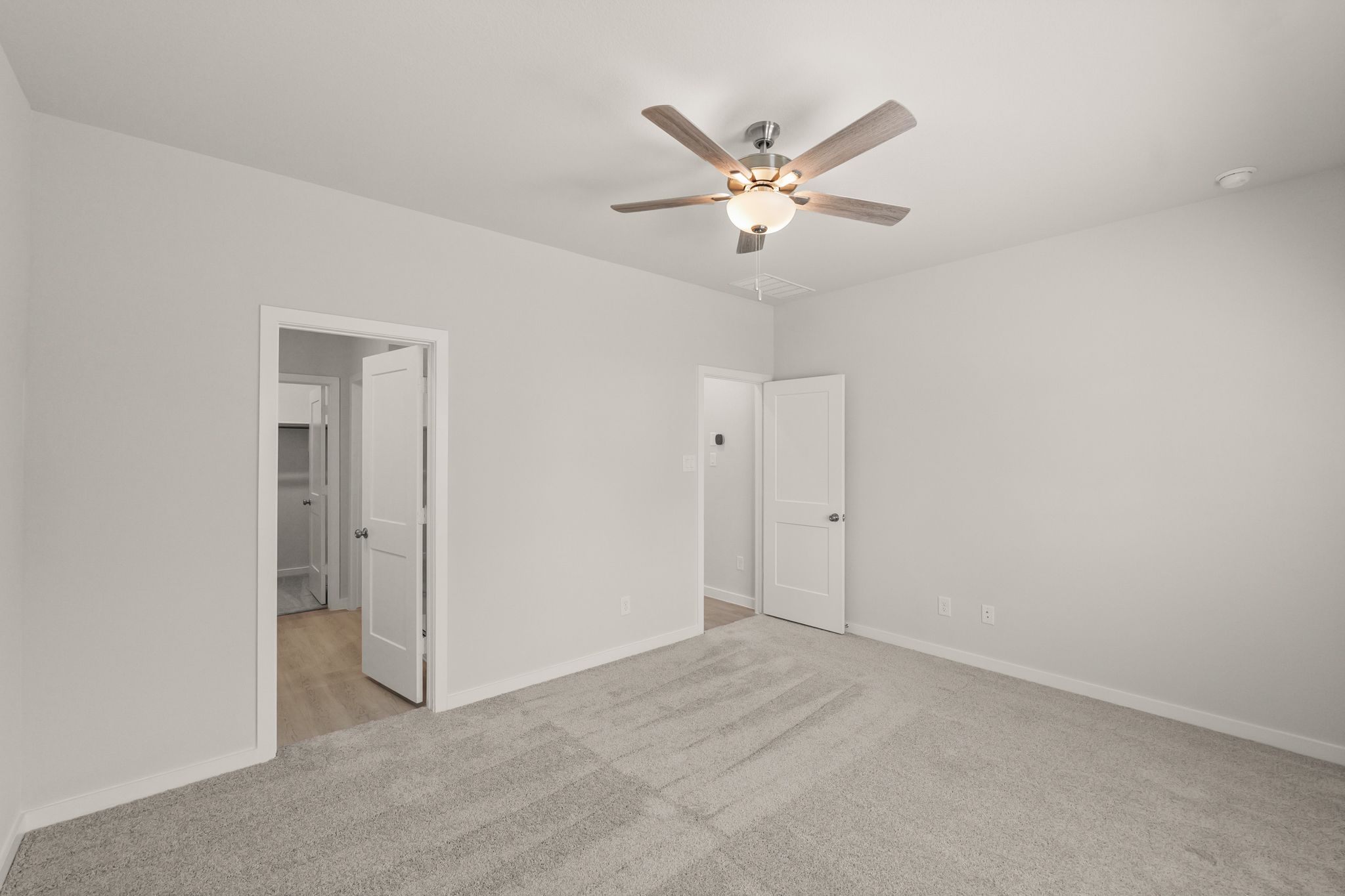 A room with a ceiling fan and white walls.