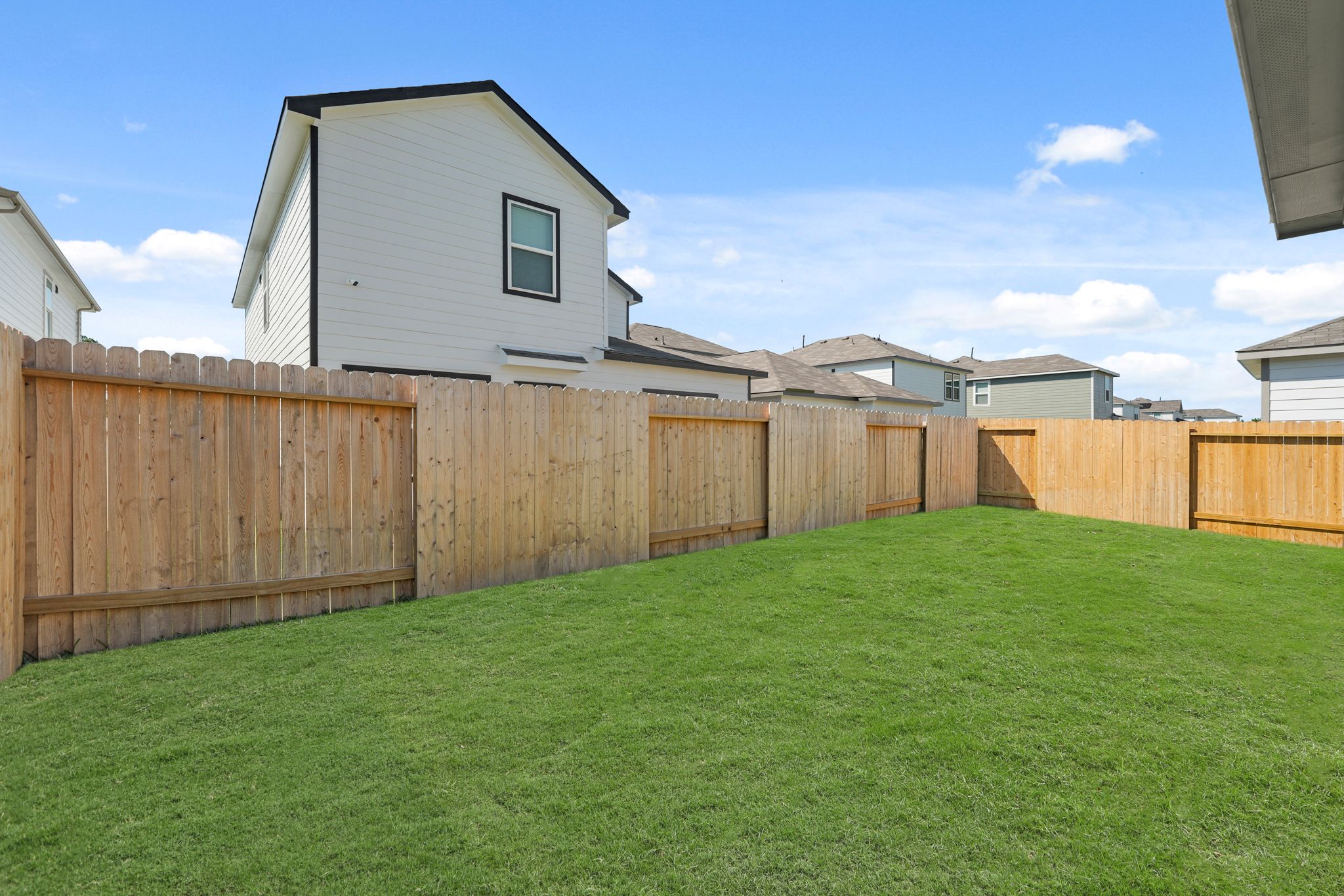 A fenced in yard with a house in the background.