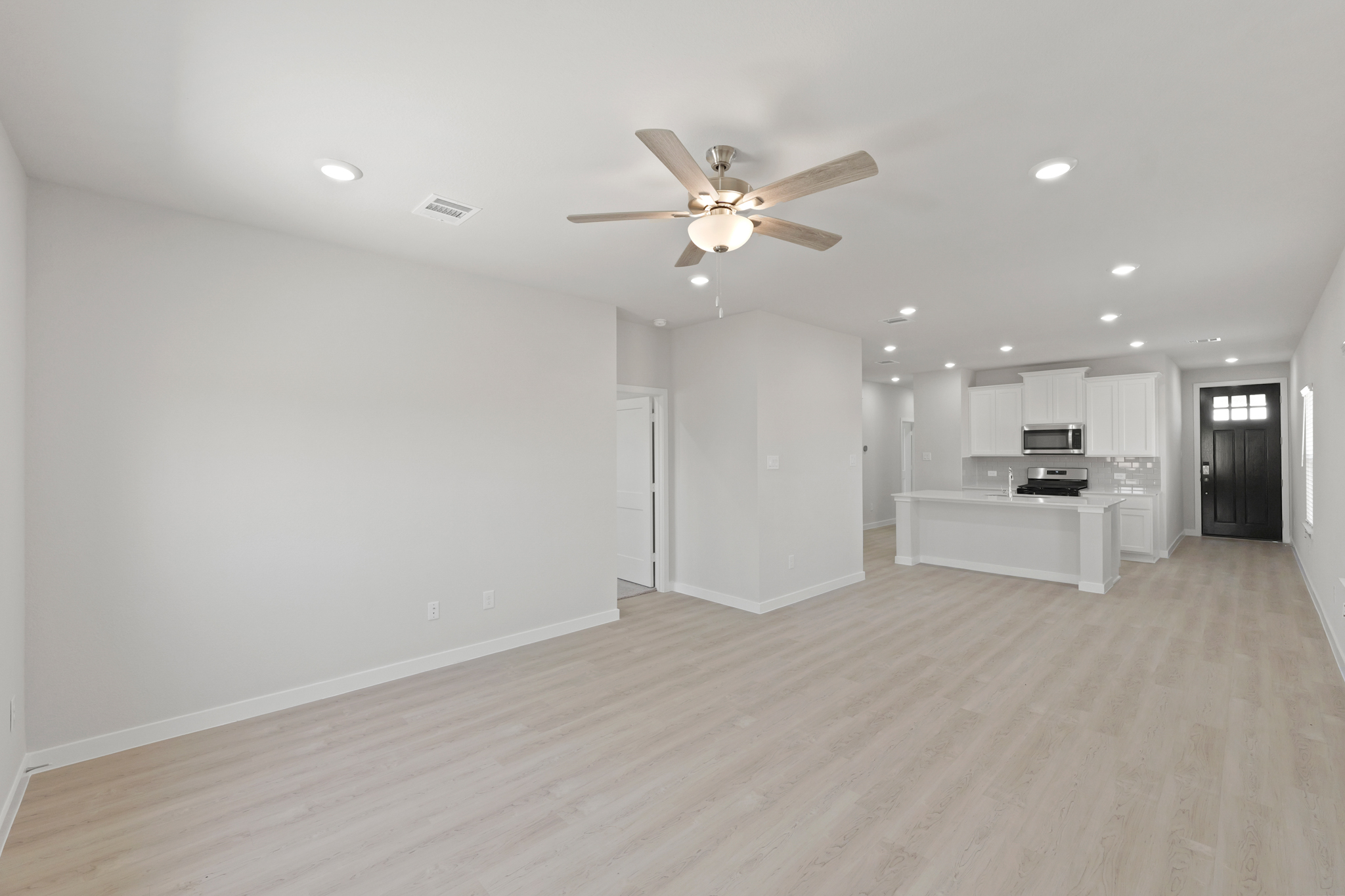 A large empty room with a ceiling fan and a wood floor.