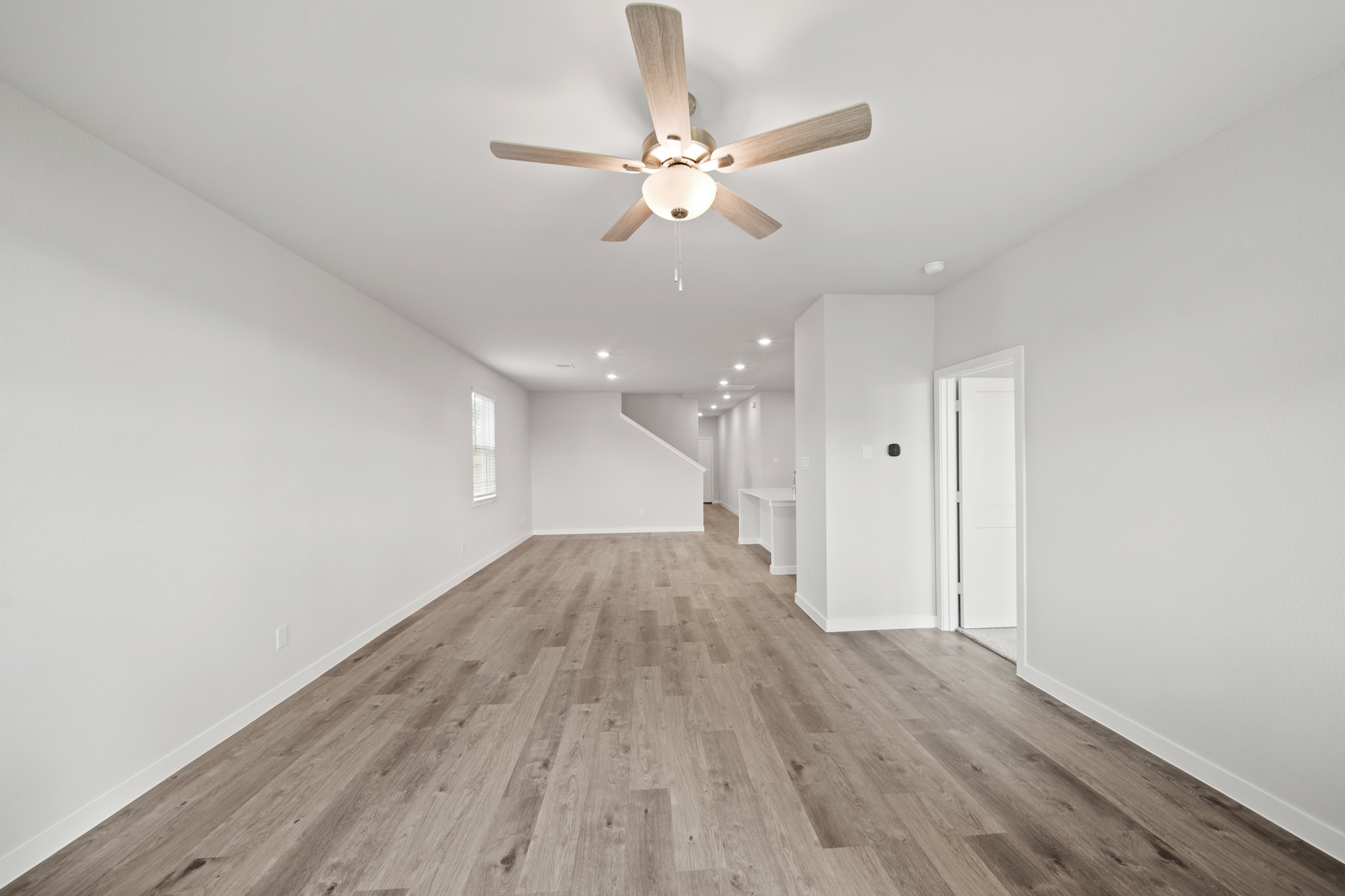 A room with a ceiling fan and wood floor.