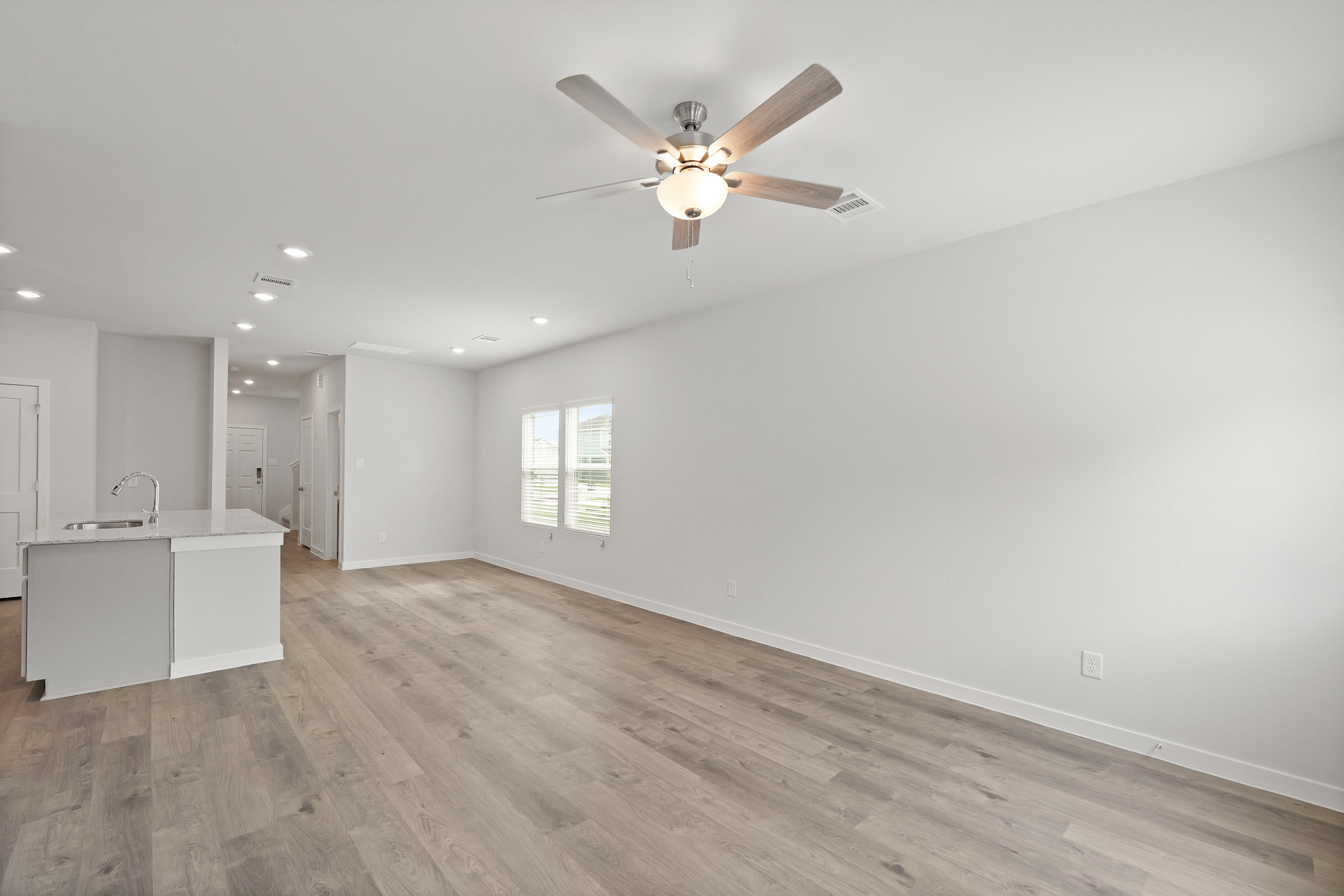 A room with a ceiling fan and a wood floor.