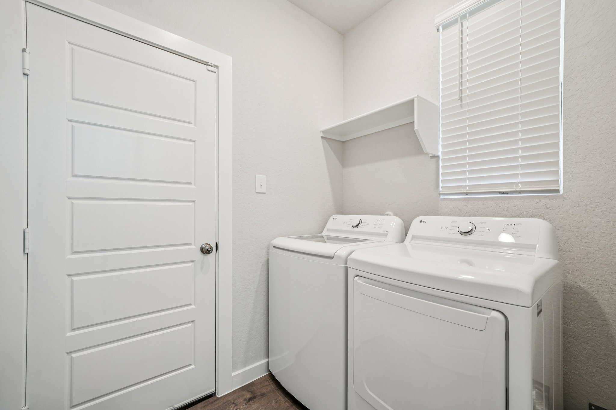A white laundry room with a white door and a white door.