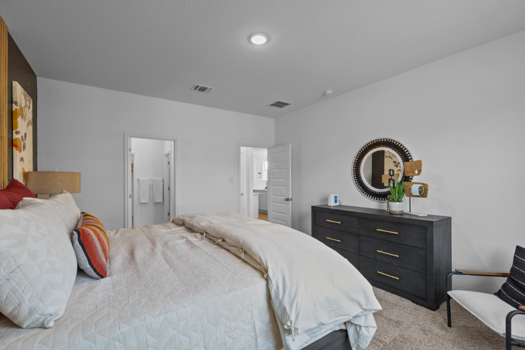 A bedroom with a bed and a mirror.