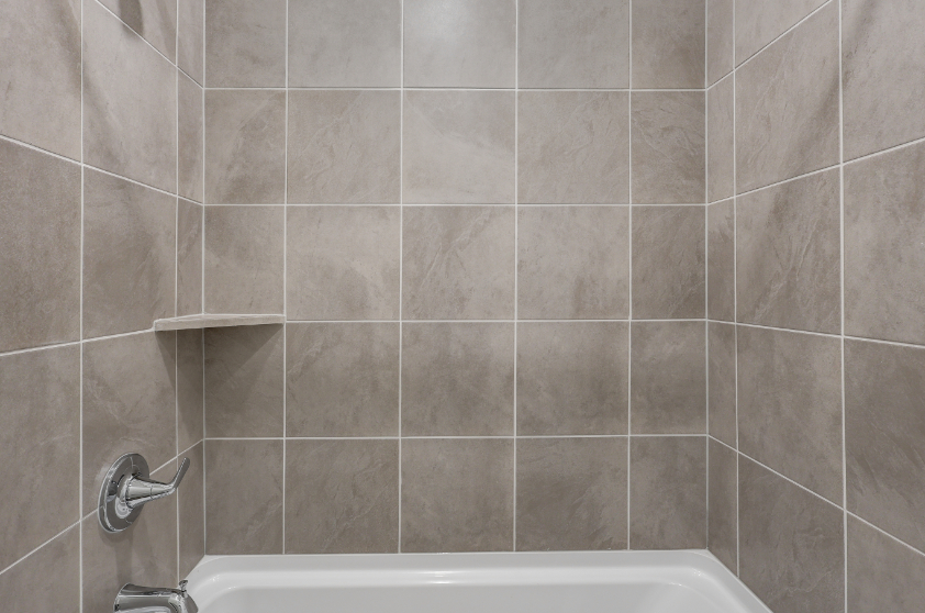 A bathtub with a tile wall.