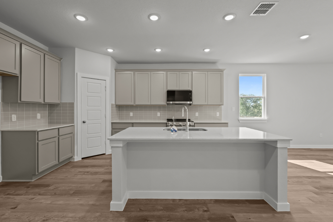 A large white kitchen with a white counter top and a white bathtub.
