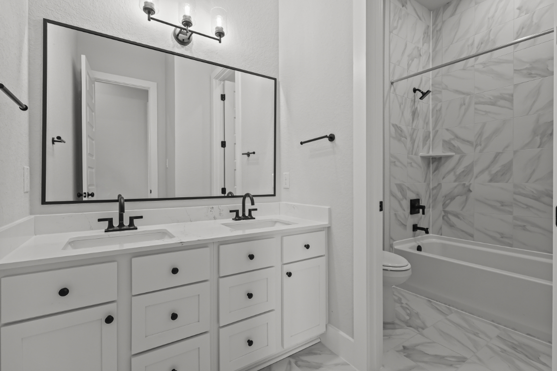 A bathroom with a tub sink and a mirror.