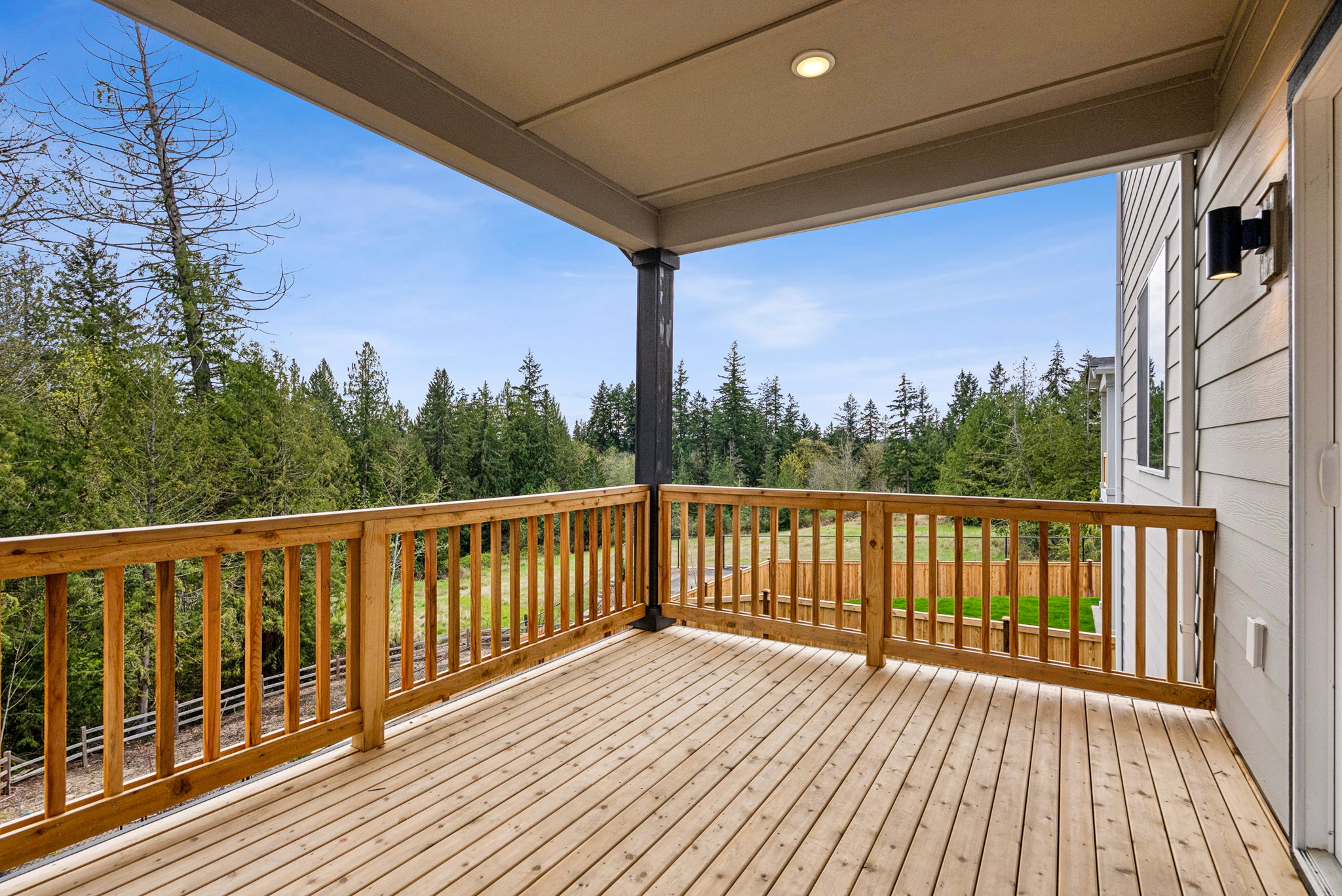 A deck with a wood railing and trees in the background.