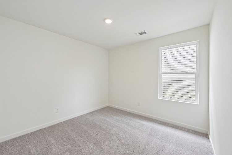 A room with a carpet and a window.